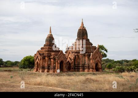 BAGAN, NYAUNG-U, MYANMAR - 3 JANVIER 2020 : deux vieux pagodes historiques de temple dans un champ d'herbe sèche ouvert Banque D'Images