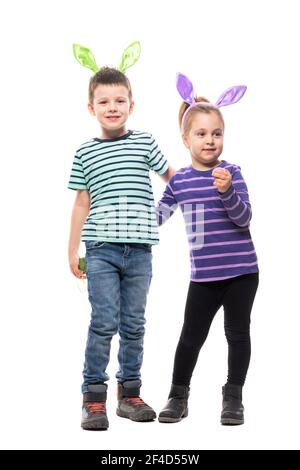 Mignon deux enfants garçon et fille embrassés portant des oreilles de lapin de Pâques posant à l'appareil photo. Corps entier isolé sur fond blanc Banque D'Images