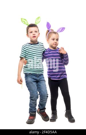 Garçon et fille frères et sœurs avec chapeau lapin de Pâques qui se serre et regarde loin regarder. Corps entier isolé sur fond blanc Banque D'Images