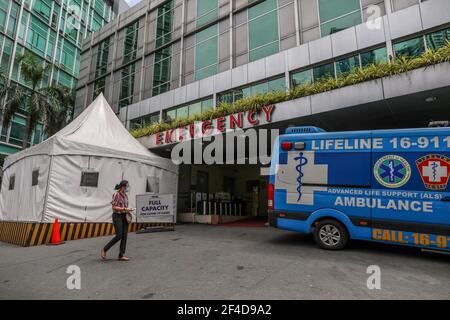 Une femme passe devant le panneau « Full Capacity for COVID-19 cases » devant un hôpital, la capitale philippine marquant une année sous quarantaine communautaire pour aider à lutter contre la propagation du coronavirus. 15 mars 2021. Philippines. Banque D'Images