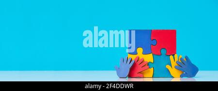 Colourfull puzzles mains sur fond bleu. Journée mondiale de sensibilisation à l'Autisme Concept Banque D'Images