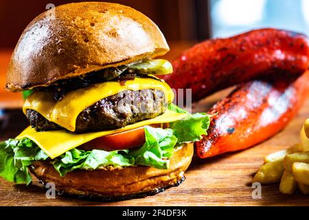 Gros plan d'un cheeseburger à la tomate, au cornichon et à la laitue, servi avec des frites et des poivrons rouges rôtis Banque D'Images