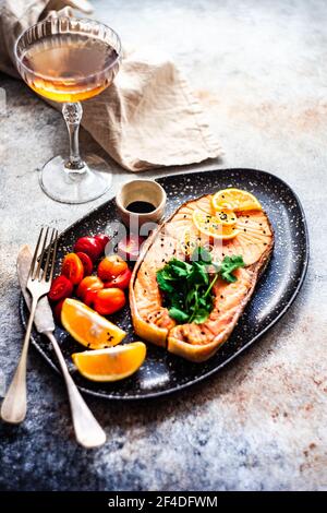 Steak de saumon grillé avec tomates, citron et un verre de vin blanc Banque D'Images