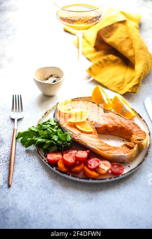 Steak de saumon grillé avec tomates, citron et un verre de vin blanc Banque D'Images