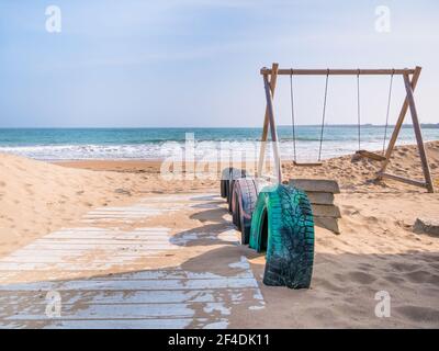 Chemin en bois sur le sable et balançoires à la plage de Mangalia, en Roumanie. Banque D'Images