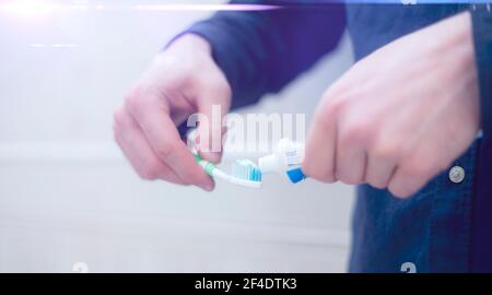 une personne pressez du dentifrice sur une brosse à dents dans la salle de bains Banque D'Images