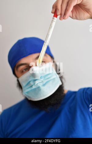 Infirmière tenant un tube. Test de dépistage du rotavirus. Homme portant un masque facial saisissant un échantillon de fèces à examiner en laboratoire Banque D'Images