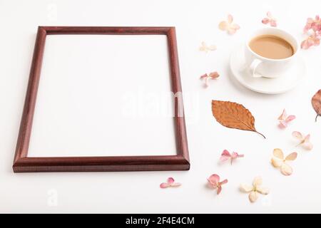 Composition avec cadre en bois, feuilles d'automne en hêtre brun, fleurs d'hortensia et tasse de café. maquette sur fond blanc. Vide, vue latérale, lif fixe Banque D'Images