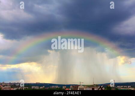 Arc-en-ciel avec pluie torrentielle au-dessus de la ville . Un effet de trouble spectaculaire Banque D'Images