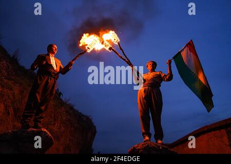 Deux Kurdes irakiens tenant des torches incendiées avec un drapeau pendant la célébration de Nowruz.la ville d'Akre dans le gouvernorat de Duhok a célébré Nowruz (Le nouvel an persan ou le nouvel an kurde).le nouvel an persan ou le nouvel an kurde est une ancienne tradition zoroastrienne célébrée par les Iraniens et les Kurdes le 20 mars de chaque année et coïncide avec l'équinoxe vernal. Banque D'Images