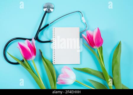 Tulipes roses et stéthoscope avec bloc-notes en spirale avec texte « Happy Doctors Day ». plan d'examen en plan, Banque D'Images
