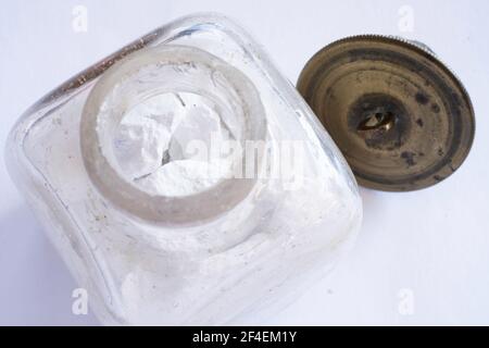 Vieux pot en verre avec des morceaux de pigments blancs séchés d'origine pour faire de la peinture à l'huile pour un peintre. Le couvercle en cuivre est à côté Banque D'Images