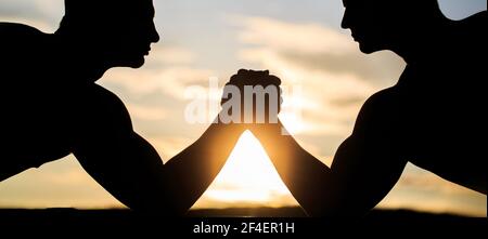 Deux hommes luttant. Silhouette de mains qui rivalisent en force. Comparaison rivalité, vs, défi, force. Coucher de soleil, lever du soleil. Rivalité, gros plan Banque D'Images