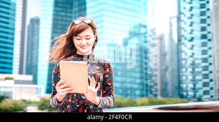 Jeune femme asiatique utilisant un appareil électronique dans une ville moderne - Concept de style de vie technologique avec une fille s'amusant avec une tablette pc périphérique Banque D'Images