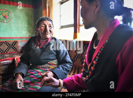 (210321) -- LHASSA, le 21 mars 2021 (Xinhua) -- Basang(L) discute avec sa fille chez elle dans le comté de Ngamring de Xigaze, dans la région autonome du Tibet du sud-ouest de la Chine, le 27 février 2021. Basang, né en 1936, avait l'habitude de grader des moutons pour un serf propriétaire de mendier sa vie avant la réforme démocratique de 1959. Elle a dû payer de la laine et du lait au propriétaire du séf comme taxe, et ne pouvait pas avoir assez de nourriture et de vêtements. 'L'hiver a été la saison la plus difficile. Il y avait huit personnes dans ma famille mais nous n'avions pas une paire de chaussures. » 'Paître les moutons et faire du travail de ferme pieds nus, j'envie vraiment les animaux avec des sabots.' Basa Banque D'Images