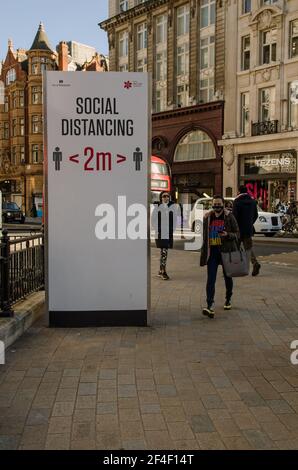 Londres, Royaume-Uni - 26 février 2021 : un grand panneau encourageant les piétons à rester à l'écart dans l'Oxford Circus, habituellement très fréquentée, dans le centre de Londres. Beaucoup de gens Banque D'Images