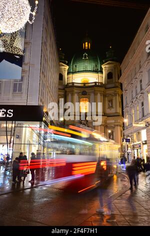 Peterskirche dans le centre historique magnifiquement décoré de Vienne avec les sentiers lumineux d'un bus qui passe sur un passage de l'Avent. Banque D'Images