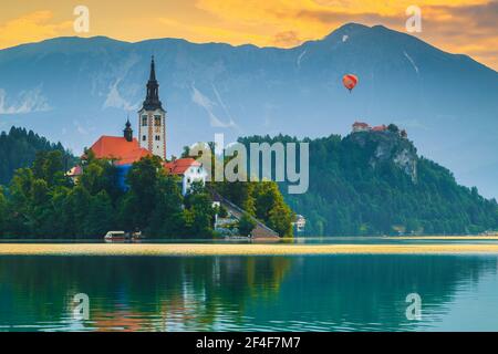 Destination alpine incroyable avec ballon d'air chaud coloré au-dessus du château de Bled et du lac à l'aube, Bled, Slovénie, Europe Banque D'Images