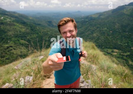 Young male vide montrant une carte de crédit. Il est debout sur le sommet de la montagne et la beauté extérieure montrant. Concept de transport facile Banque D'Images