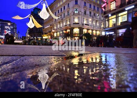 Shopping de Noël et visite de la ville de Vienne sur la rue Graben décorée avec goût avec réflexion sur une flaque d'eau au crépuscule. Banque D'Images