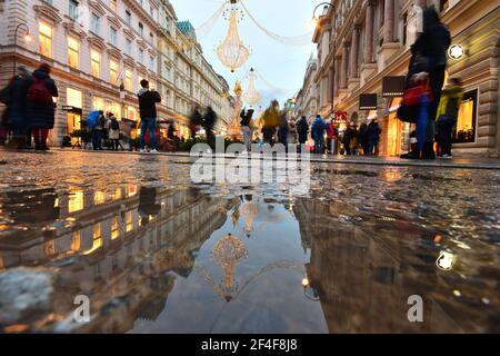 Shopping de Noël et visite de la ville de Vienne sur la rue Graben décorée avec goût avec réflexion sur une flaque d'eau au crépuscule. Banque D'Images