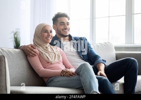 Une famille musulmane joyeuse assise sur un canapé à la maison Banque D'Images