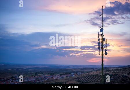 Antennes de station de radiodiffusion en haut de la colline de la petite ville. Paysage rural au coucher du soleil Banque D'Images