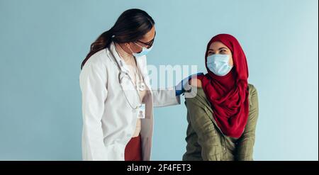 Femme musulmane et femme médecin portant un masque de protection. Femme islamique chez un médecin pour avoir reçu le vaccin. Banque D'Images