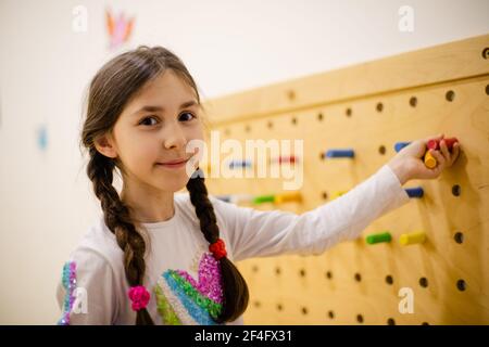 la fille joue avec des panneaux perforés en bois avec des chevilles rondes Banque D'Images