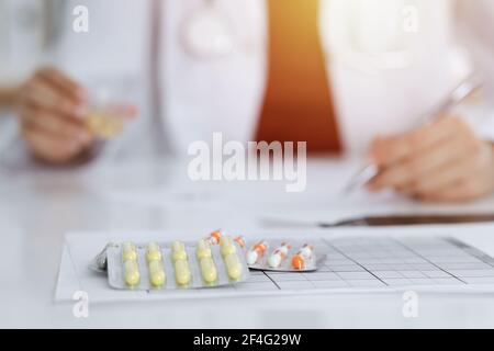 Femme-médecin inconnu remplit la forme de prescription dans la salle ensoleillée, gros plan Banque D'Images