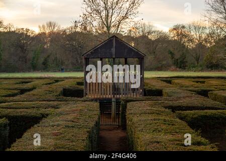 Une cabine en bois à l'intérieur d'un labyrinthe dans un parc à coucher de soleil Banque D'Images