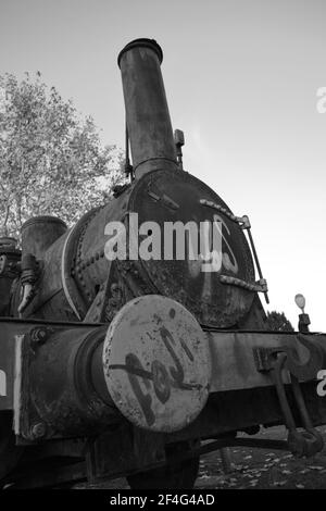 Noir et blanc - train à moteur à vapeur ancien au parc de Córdoba. Andalucía, Espagne. Machine à vapeur rouillée laissée comme monument ou décoration dans le parc de Córdoba. Sombre. Banque D'Images