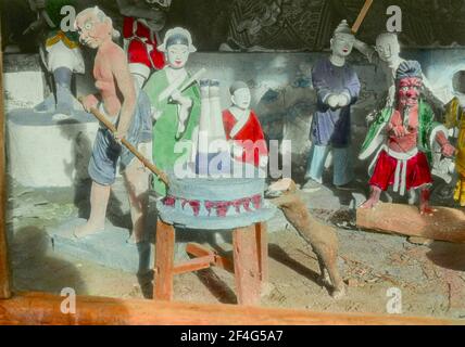 Une vignette sculpturale colorée avec une variété de figures humaines et plusieurs démons à la peau rouge, dont l'un grine une figure humaine renversée dans une pierre de moulin, probablement dépeignant l'« Enfer de broyage », Sichuan, Chine, 1917. De la collection de photographies Sidney D. Gamble. () Banque D'Images
