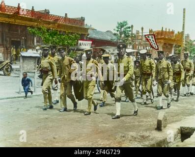 Les étudiants Tsinghua portant des uniformes de scoutisme sont emportés en prison pour avoir participé au mouvement du 4 mai, avec un petit garçon qui court sur le bord de la route à côté d'eux, Beijing, Chine, 1919. De la collection de photographies Sidney D. Gamble. () Banque D'Images