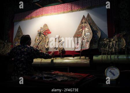 Le maître de marionnettes (dalang) interprète la représentation de wayang kulis « The Death of Kumbakarna » au Musée Sonobudoyo de Yogyakarta, dans le centre de Java, en Indonésie. Les marionnettes Kumbhakarna sont vues sur l'écran à gauche tandis que les figures allégoriques du Gunungan représentant à la fois l'arbre de vie javanais et la montagne Cosmique (Mont Meru) sont vues de chaque côté de l'écran. Le théâtre traditionnel de marionnettes connu sous le nom de wayang kulis est répandu sur les îles de Java et Bali en Indonésie. Chaque exécution de wayang kulis se poursuit environ huit heures par nuit sans intermissions et un seul Banque D'Images