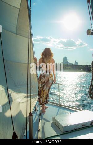 Belle femme à bord du yacht. Une femme regarde le soleil couchant. Correctement construit figure d'une femme est bon dans les rayons du coucher du soleil. Banque D'Images