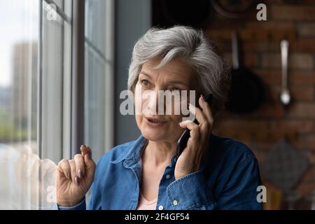 Une heureuse femme hispanique à la retraite s'est engagée dans une conversation agréable au téléphone Banque D'Images