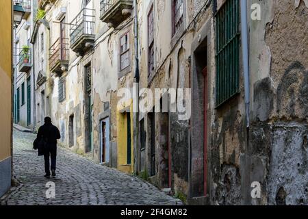 Homme marchant dans l'une des ruelles du vieux Porto, Portugal. Banque D'Images