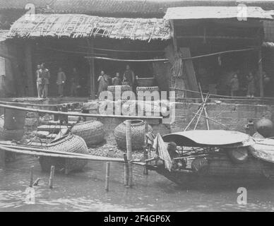 Personnes sur une rive de rivière, grand panier dans l'eau, Chine, Grand Canal (Chine), 1908. De la collection de photographies Sidney D. Gamble. () Banque D'Images