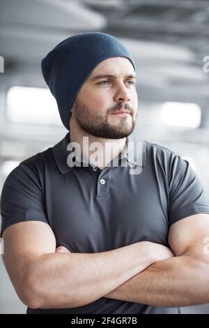 Portret un beau jeune homme avec une barbe qui regarde par la fenêtre. Image d'un homme heureux portant des vêtements habillés sur fond gris. Banque D'Images