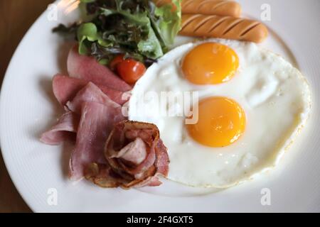 Petit déjeuner avec les œufs, bacon, saucisses, haricots, pain grillé, salade fraîche et des fruits sur la table en bois Banque D'Images