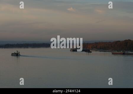 Vue sur les remorqueurs, les barges et les poussettes depuis le terminal des conteneurs sur la rivière Columbia entourée d'arbres et de buissons pendant le coucher du soleil sous le ciel violet. Banque D'Images