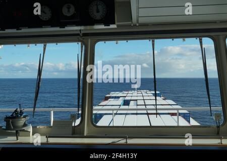 Voir depuis la fenêtre du pont de navigation du navire à conteneurs sur les conteneurs couverts de neige en cours dans l'océan Pacifique. Banque D'Images