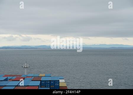 Voir le navire-conteneur chargé de conteneurs sur la montagne recouverte de neige à l'approche de Vancouver, en Colombie-Britannique. Banque D'Images