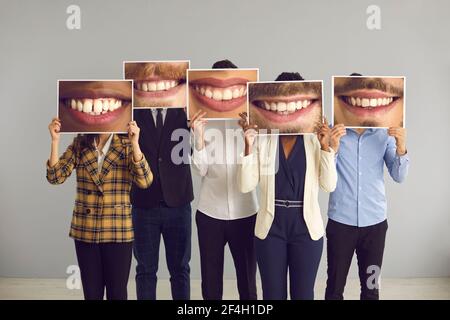 Groupe de personnes diverses se cachant derrière de grandes photos amusantes de sourires heureux et séduisants Banque D'Images
