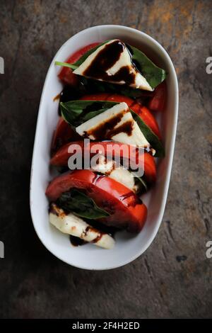 Salade Caprese au basilic frais et aux tomates sur fond de bois dans la lumière mystique Banque D'Images