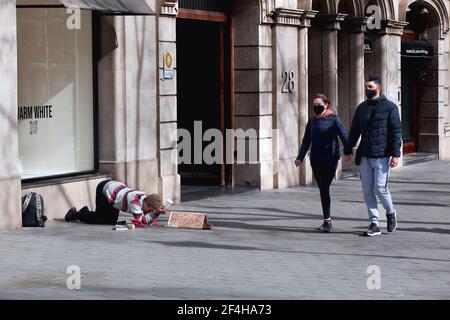 Un couple qui marche devant un homme mendiant dans la rue. Banque D'Images