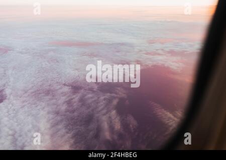 À travers la fenêtre de l'avion vue des nuages blancs dans le ciel sans fin Pendant le vol au lever du soleil dans les Dolomites Italie Banque D'Images