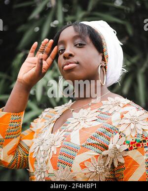 Jeune femme africaine en kkerchien regardant la caméra contre l'usine en été Banque D'Images