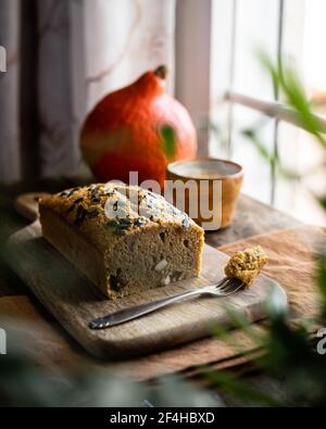 À travers les feuilles de maison délicieux pain de citrouille fraîchement cuit avec sain grains placés sur une planche à découper en bois dans une cuisine légère Banque D'Images